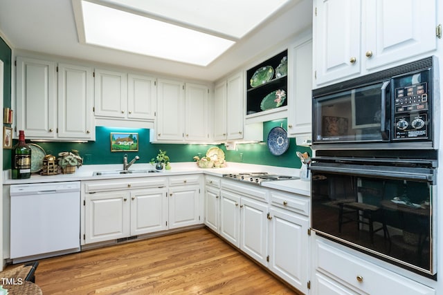 kitchen with sink, light hardwood / wood-style flooring, white cabinetry, and black appliances