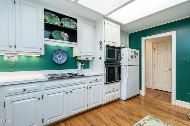 kitchen with white cabinetry, black appliances, and light hardwood / wood-style floors