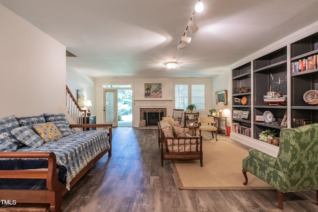 living room with rail lighting, dark hardwood / wood-style floors, built in features, and a fireplace