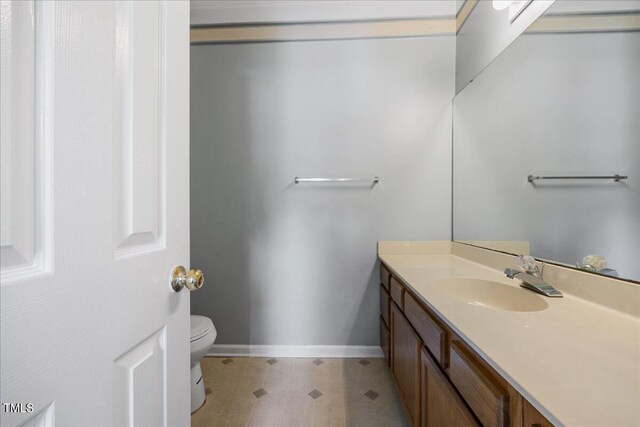 bathroom featuring vanity with extensive cabinet space, tile flooring, and toilet