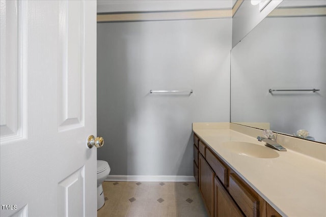 bathroom with toilet, baseboards, and vanity