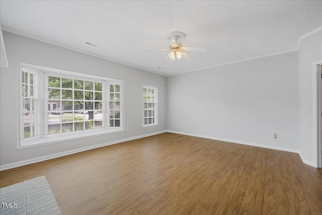 empty room featuring a textured ceiling, dark wood-type flooring, visible vents, baseboards, and ornamental molding