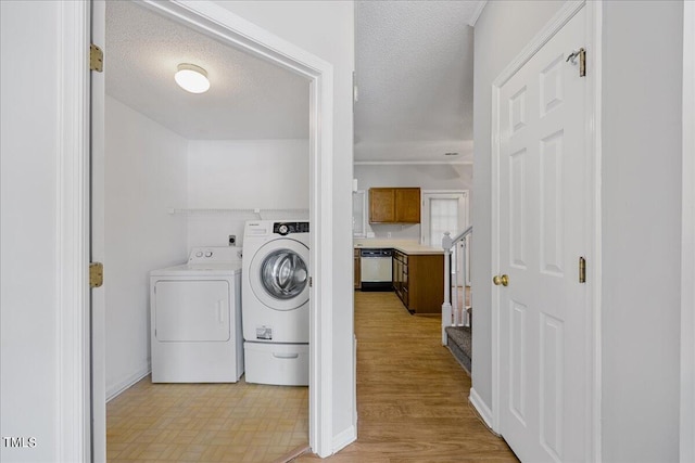 clothes washing area with a textured ceiling, laundry area, and independent washer and dryer