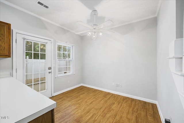 unfurnished dining area with ornamental molding, ceiling fan, and light wood-type flooring