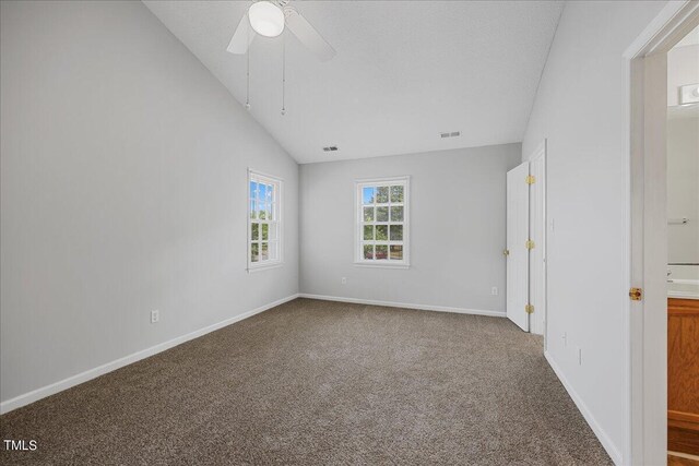 carpeted spare room featuring ceiling fan and vaulted ceiling