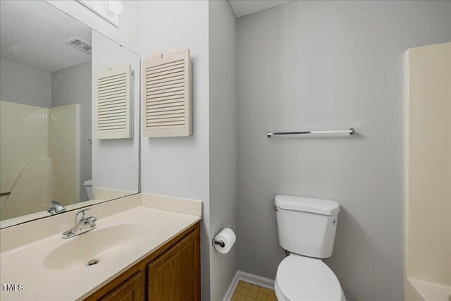 full bathroom featuring vanity with extensive cabinet space, tile floors, toilet, and a textured ceiling