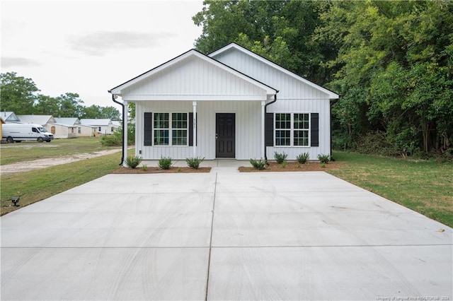 modern farmhouse with a porch, a front lawn, and board and batten siding