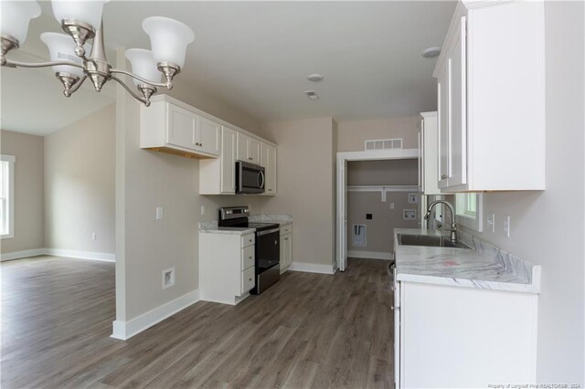 kitchen with wood-type flooring, white cabinetry, light stone countertops, an inviting chandelier, and stainless steel appliances