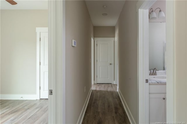 hall with a sink, dark wood finished floors, and baseboards