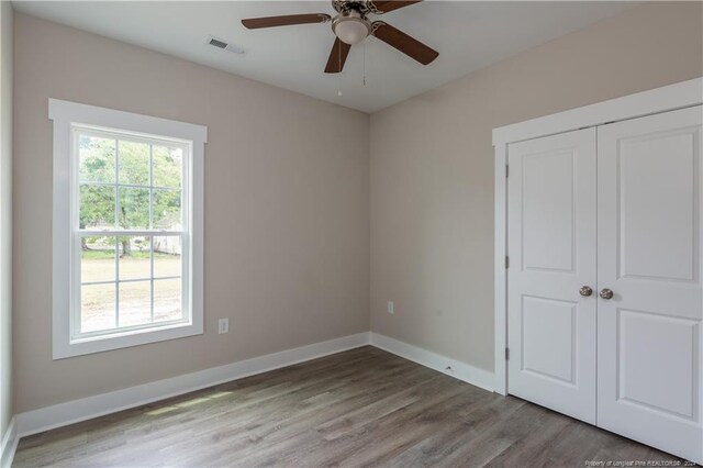 unfurnished bedroom with ceiling fan, light wood-type flooring, and a closet