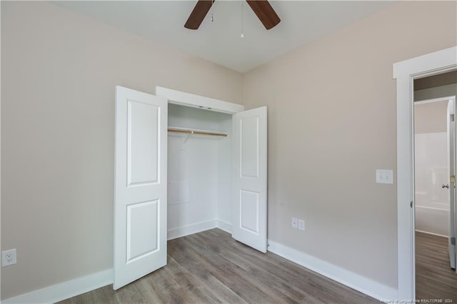 unfurnished bedroom featuring a ceiling fan, a closet, baseboards, and wood finished floors