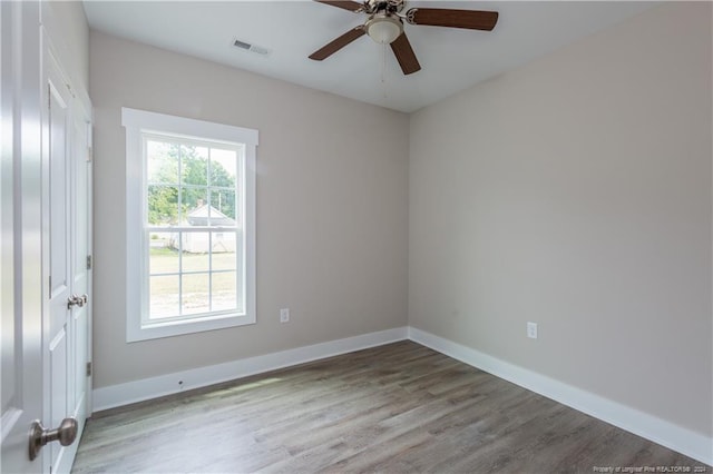 empty room featuring ceiling fan, wood finished floors, visible vents, and baseboards