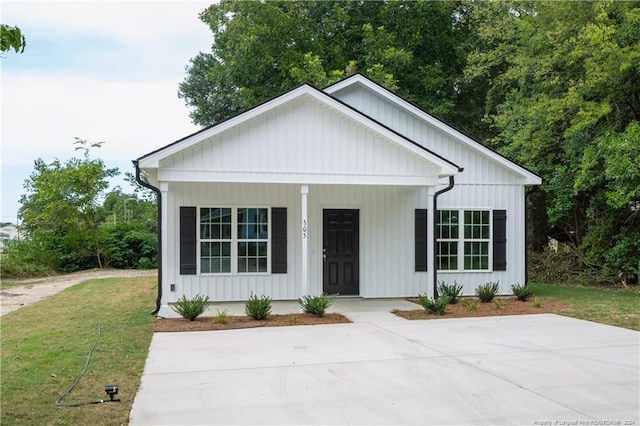 modern inspired farmhouse with covered porch, a front lawn, and board and batten siding