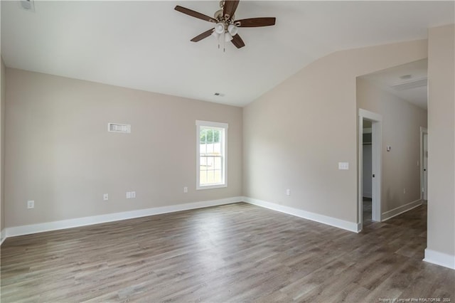 empty room with ceiling fan, wood finished floors, visible vents, baseboards, and vaulted ceiling