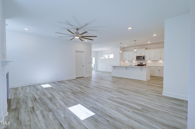 154 Swain St, Clayton, NC 27527 - unfurnished living room featuring light hardwood / wood-style floors, ceiling fan, and sink
