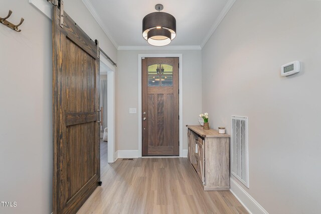 foyer featuring a barn door, light hardwood / wood-style flooring, and crown molding