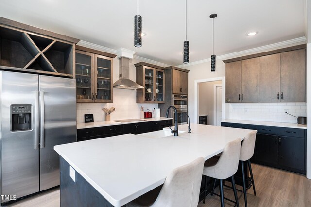 kitchen with stainless steel fridge, wall chimney exhaust hood, and a kitchen island with sink