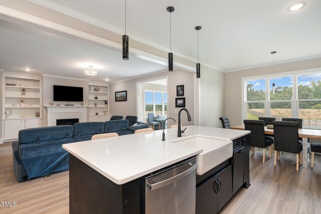 kitchen featuring stainless steel dishwasher, a healthy amount of sunlight, a center island with sink, and pendant lighting