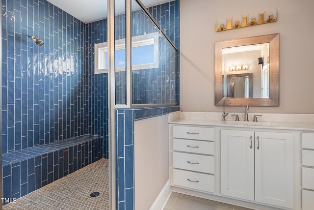 bathroom with a tile shower, vanity, and tile patterned floors