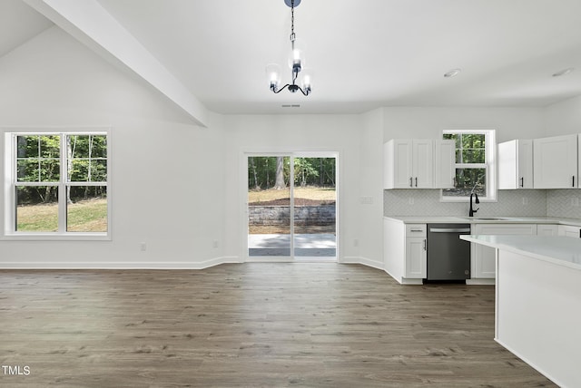 kitchen with stainless steel dishwasher, decorative light fixtures, white cabinetry, and hardwood / wood-style flooring