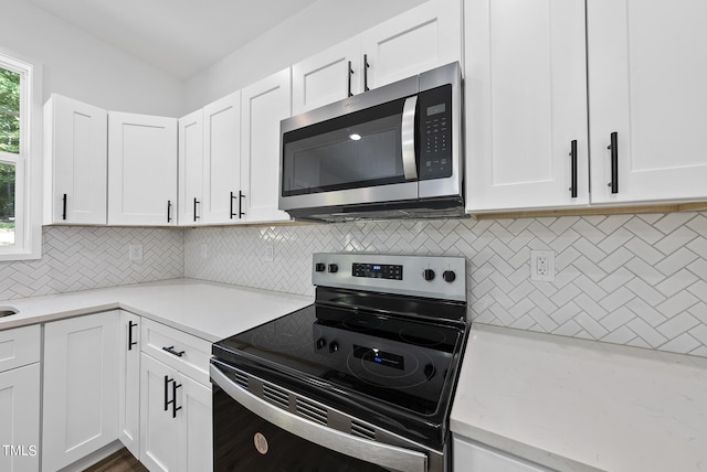 kitchen with decorative backsplash, light stone counters, stainless steel appliances, and white cabinetry