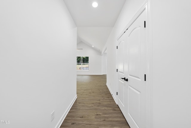 corridor with dark hardwood / wood-style floors and vaulted ceiling