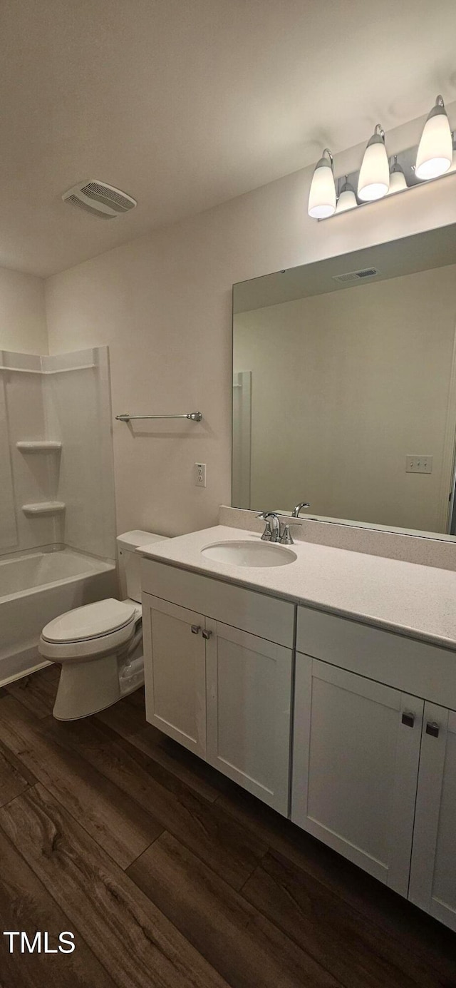 full bathroom featuring hardwood / wood-style flooring, vanity, toilet, and shower / washtub combination