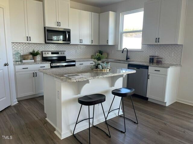 466 Saint Clair Dr, Fuquay Varina, NC 27526 - kitchen with stainless steel appliances, a sink, dark wood-style floors, and white cabinetry