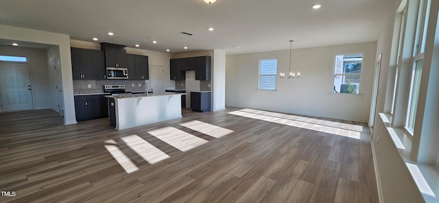 kitchen featuring appliances with stainless steel finishes, open floor plan, a sink, and backsplash