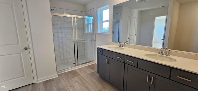 full bath featuring a stall shower, a sink, and wood finished floors