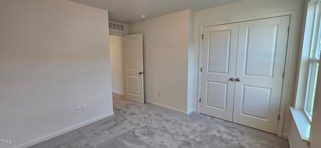 unfurnished bedroom featuring baseboards, carpet, visible vents, and a closet