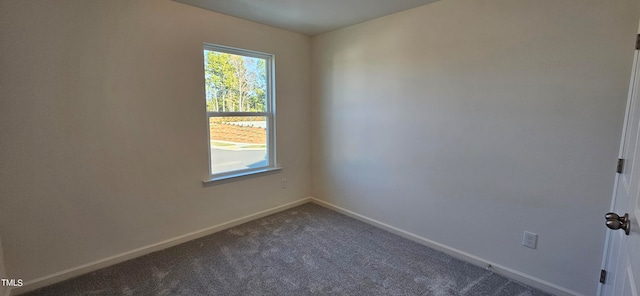 empty room featuring dark colored carpet and baseboards