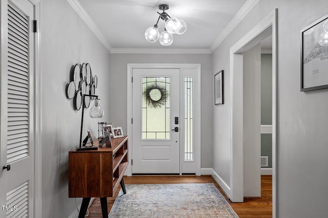 foyer with a notable chandelier, wood-type flooring, and crown molding