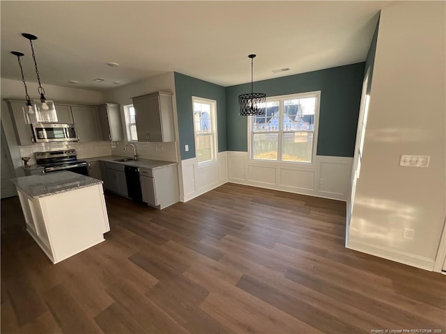 kitchen featuring sink, pendant lighting, stainless steel appliances, dark hardwood / wood-style flooring, and light stone countertops