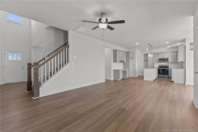 unfurnished living room with sink, hardwood / wood-style floors, and ceiling fan