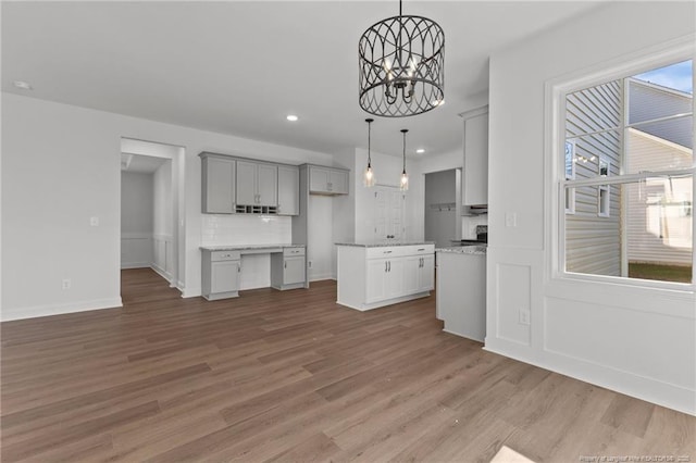 kitchen with gray cabinets, decorative light fixtures, a notable chandelier, and hardwood / wood-style flooring