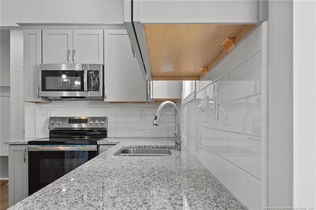 kitchen with sink, stainless steel appliances, white cabinets, and light stone counters