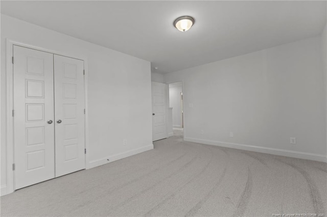 unfurnished bedroom with a closet and light colored carpet