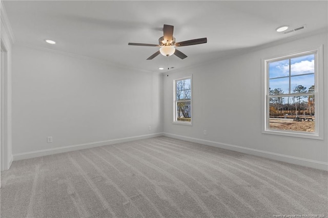 empty room with ceiling fan, crown molding, and light colored carpet