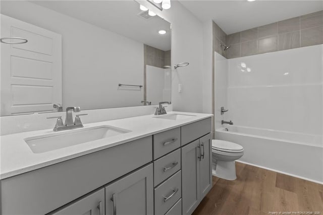 full bathroom with hardwood / wood-style flooring, vanity, tub / shower combination, and toilet