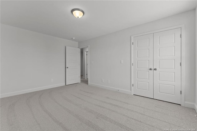 unfurnished bedroom featuring a closet and light colored carpet