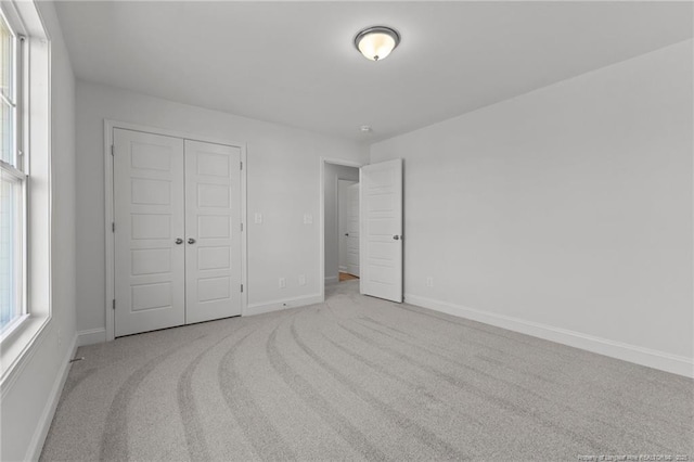 unfurnished bedroom with light carpet and a closet