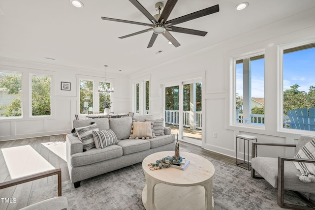 sunroom / solarium featuring ceiling fan with notable chandelier