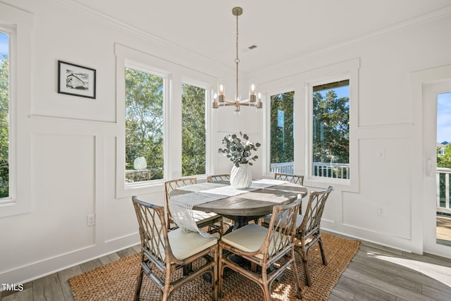 dining space featuring hardwood / wood-style flooring, ornamental molding, and an inviting chandelier