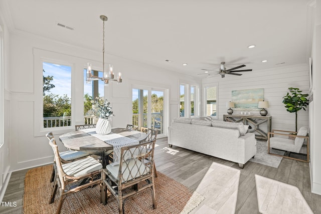 dining area featuring hardwood / wood-style flooring, ornamental molding, and ceiling fan with notable chandelier