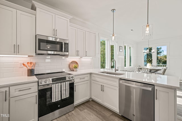 kitchen with pendant lighting, tasteful backsplash, white cabinetry, sink, and stainless steel appliances