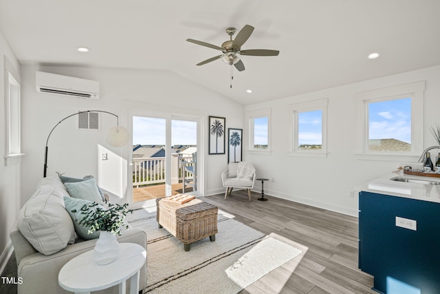 living room with lofted ceiling, sink, light hardwood / wood-style flooring, an AC wall unit, and ceiling fan