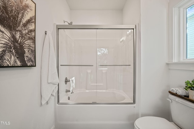 bathroom with toilet and bath / shower combo with glass door