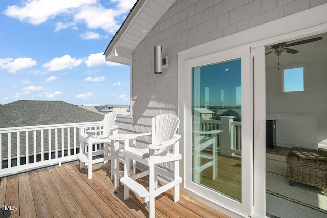 wooden balcony with a deck and ceiling fan