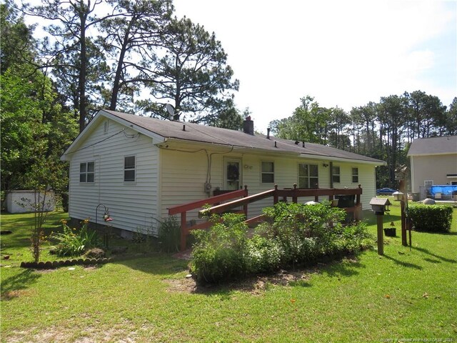 rear view of property with a wooden deck and a lawn